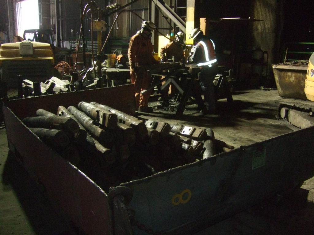 Workers sorting metal parts in a factory.